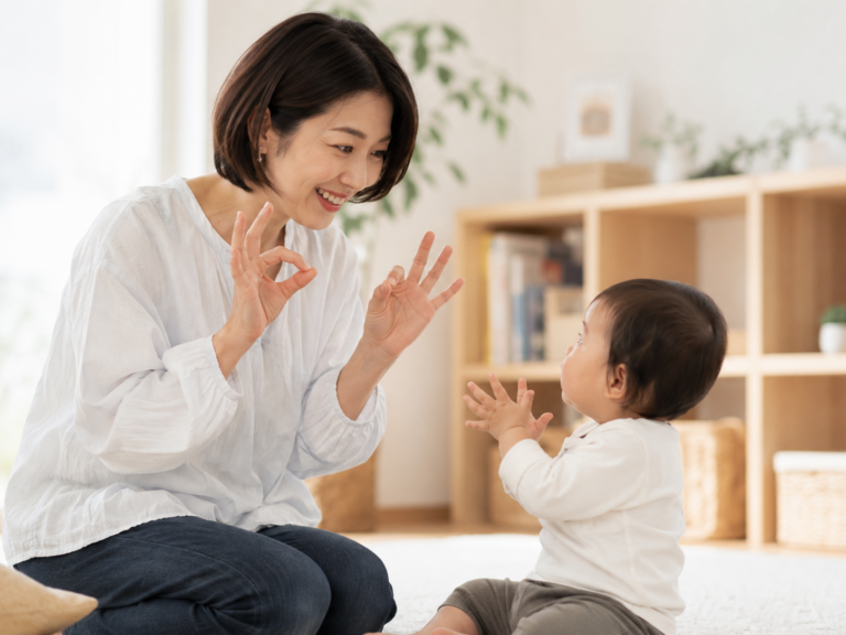 笑顔でベビーサインを見せ合う母親と赤ちゃん